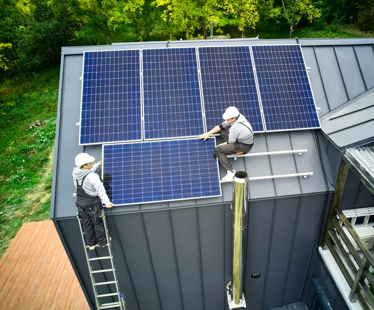 Dos operarios colocan paneles sobre un tejado, imagen de una instalación de placas solares en Toledo y su coste